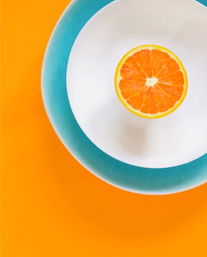 half of an orange in a bottle with blue border in a orange background.