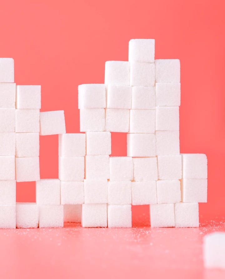 structure made of pilled suggar cubes in a pink table and background.